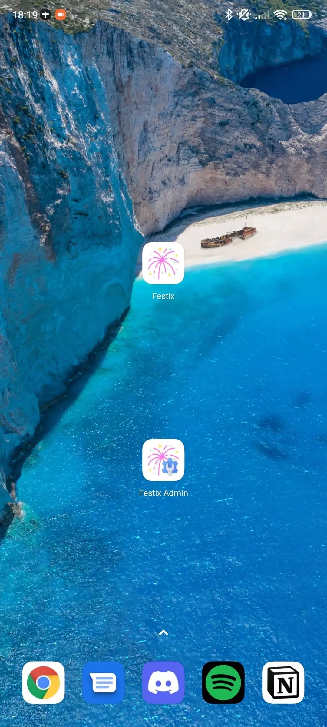 Smartphone home screen with beach wallpaper and various app icons like Google Chrome, Spotify, and Festix.