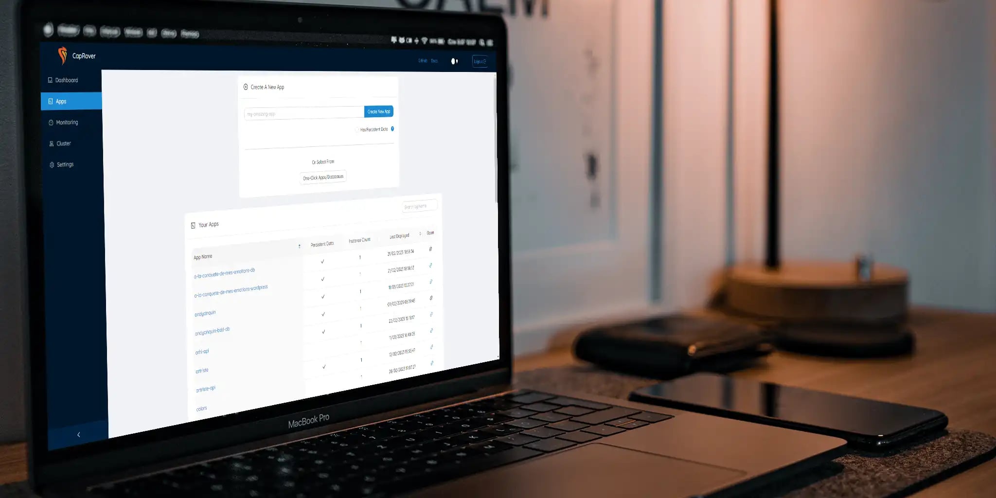 Laptop on desk displaying web application interface, smartphone and notebook beside it