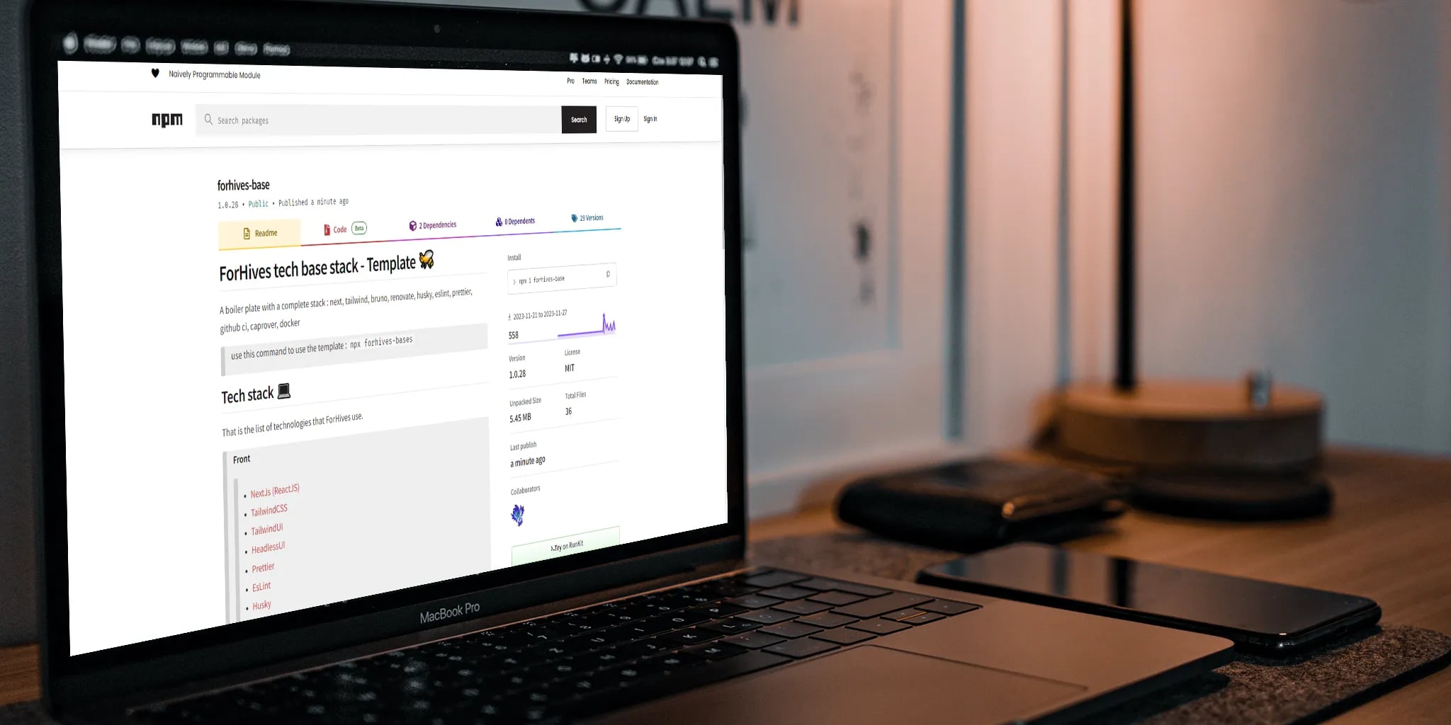 A laptop on a desk displaying an npm package page with smartphone and other desktop items