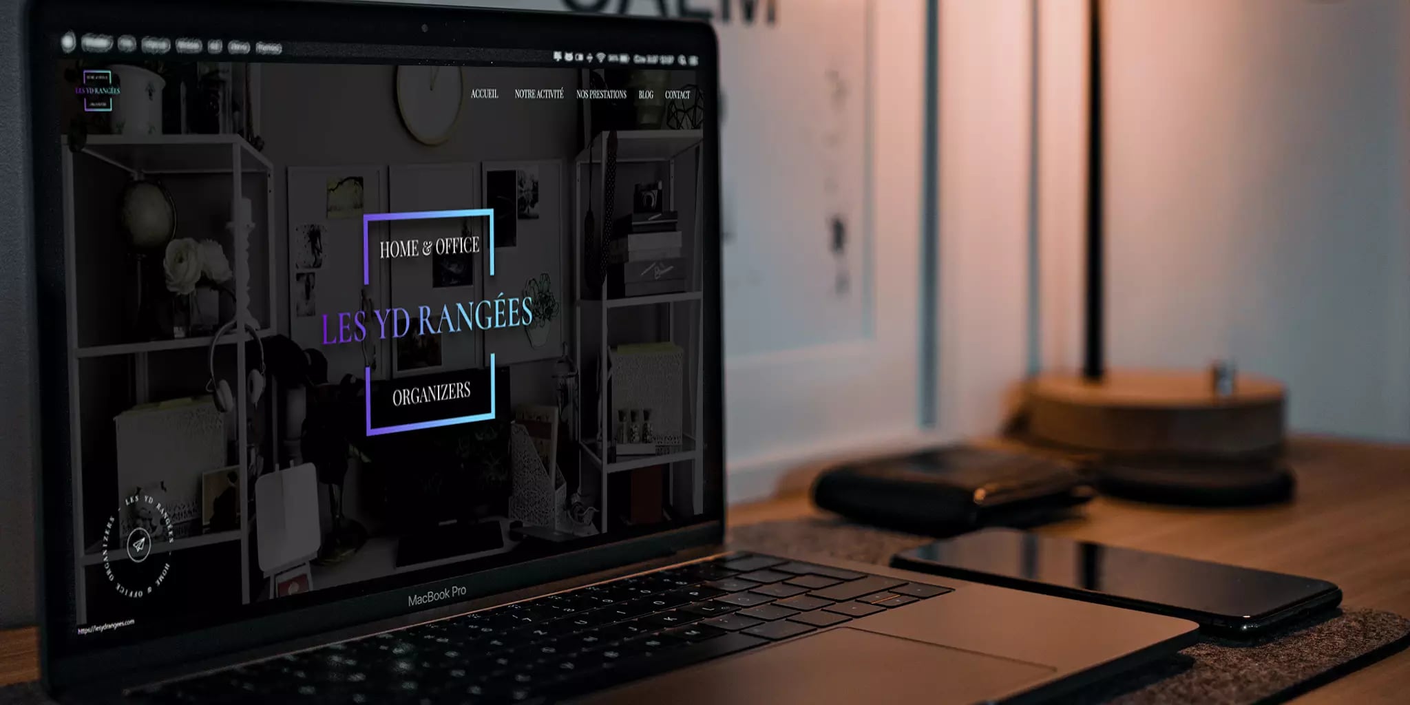 Cozy home office workspace with laptop displaying website and smartphone on desk